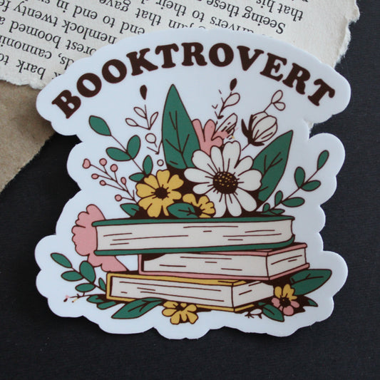 Sticker with 'Booktrovert' design featuring books and flowers on a dark background