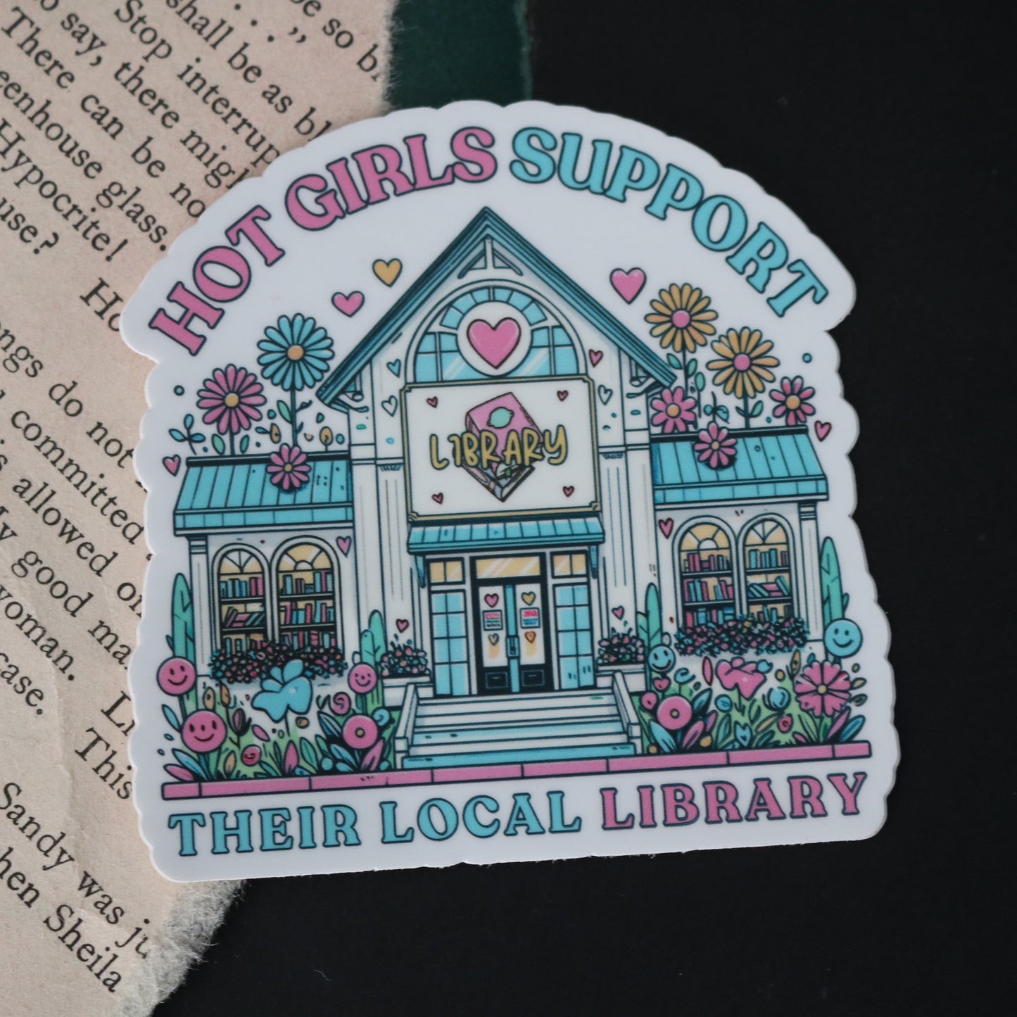 A vinyl sticker with an illustration of a library building, surrounded by floral designs and text that reads 'Hot Girls Support Their Local Library'.